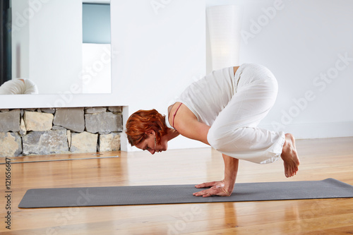 Yoga Crow Pose in wooden floor gym