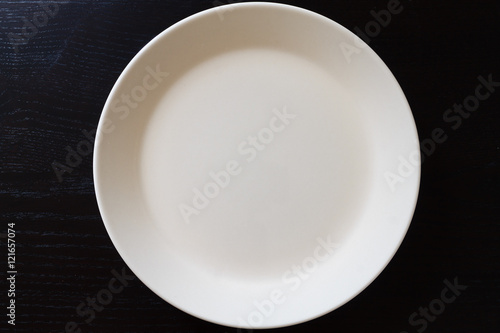 Empty white plate on black wooden table