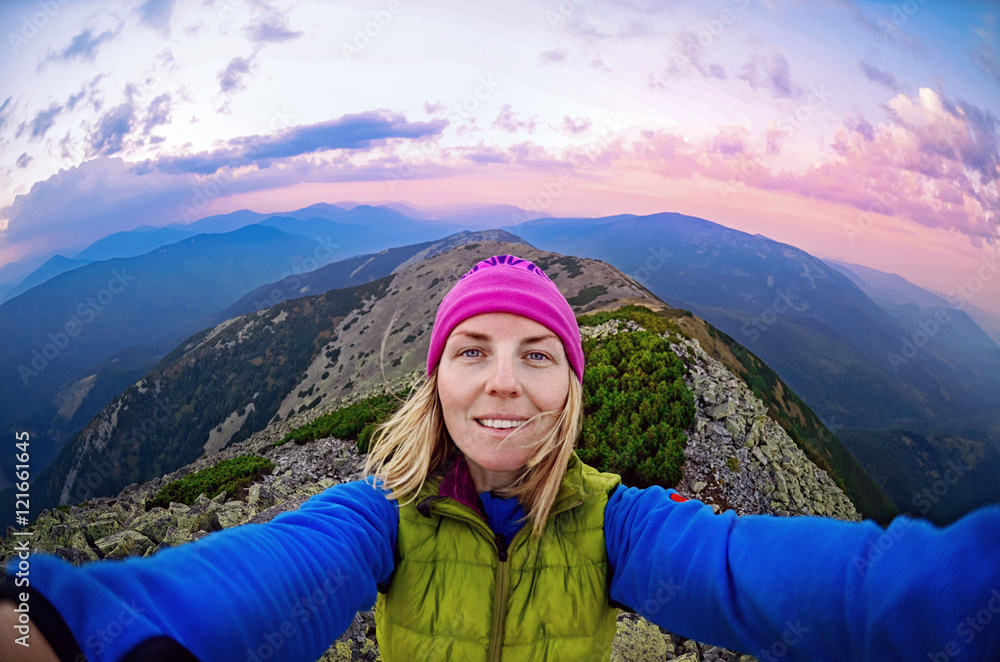 Smiling young woman takes a selfie  on  the  top of   mount Great Sivulja  ,Carpathian ,Ukraine
