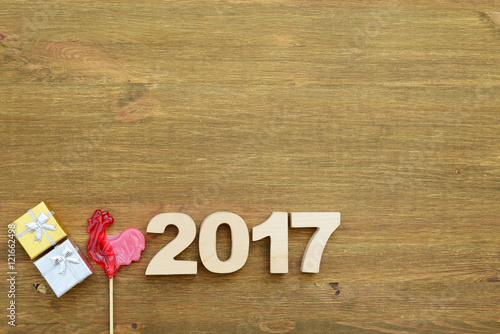 Red rooster, symbol of 2017 on the Chinese calendar. Lollipop in the form of a red rooster on a wooden background