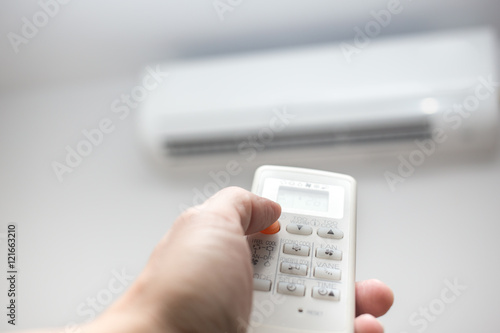 hand with remote control air conditioner blur background
