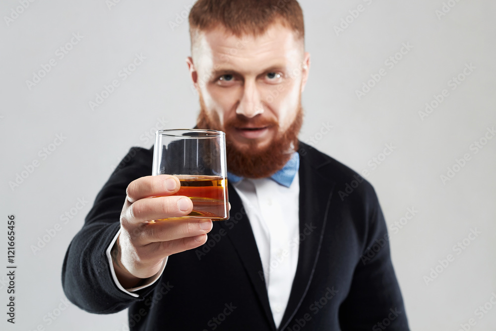 stylish handsome bearded man offers whiskey.Elegant man keeps and holds a glass stylish handsome bearded man offers whiskey.Elegant man keeps and holds a glass
