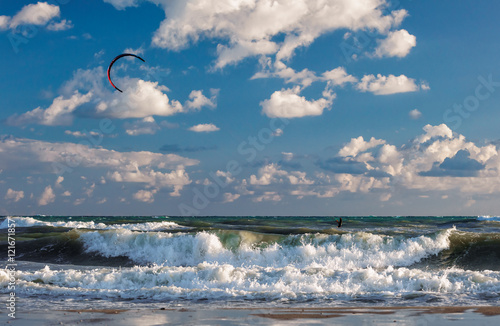 Kitesurfer riding his kite through waves of stormy sea