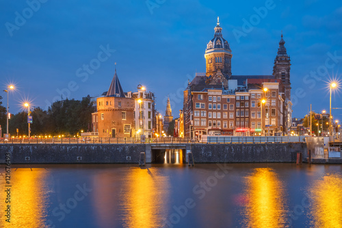 Night panoramic city view of Amsterdam canal, bridge and Basilica of Saint Nicholas, Holland, Netherlands. Long exposure.