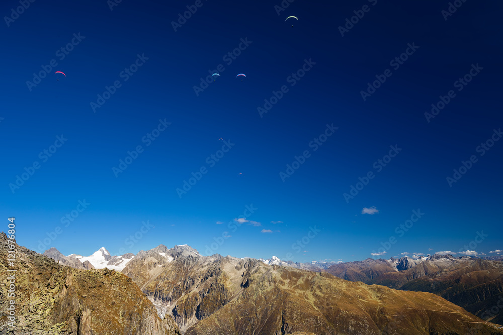 Paragliders enjoying majestic view to Swiss Alps from the top of Eggishorn, Valais, Switzerland