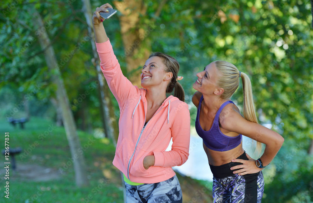 Obraz premium Shot of two females taking selfie during a quick break while out for a trail run using phone