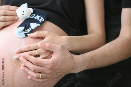 Petite chaussette assorti d'un nounours sur le ventre d'une femme enceinte.