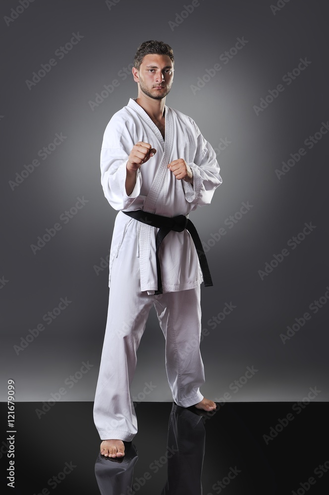 Handsome young male karate doing kata on the gray background Handsome young male karate doing kata on the gray background
