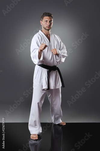 Handsome young male karate doing kata on the gray background