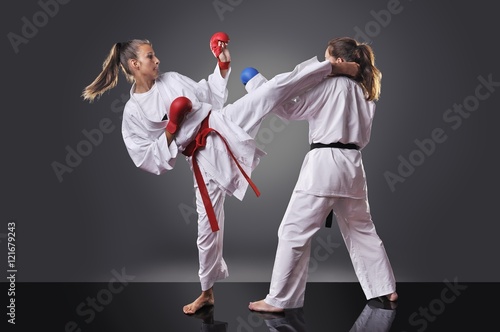 Two female young karate fighting on the gray background