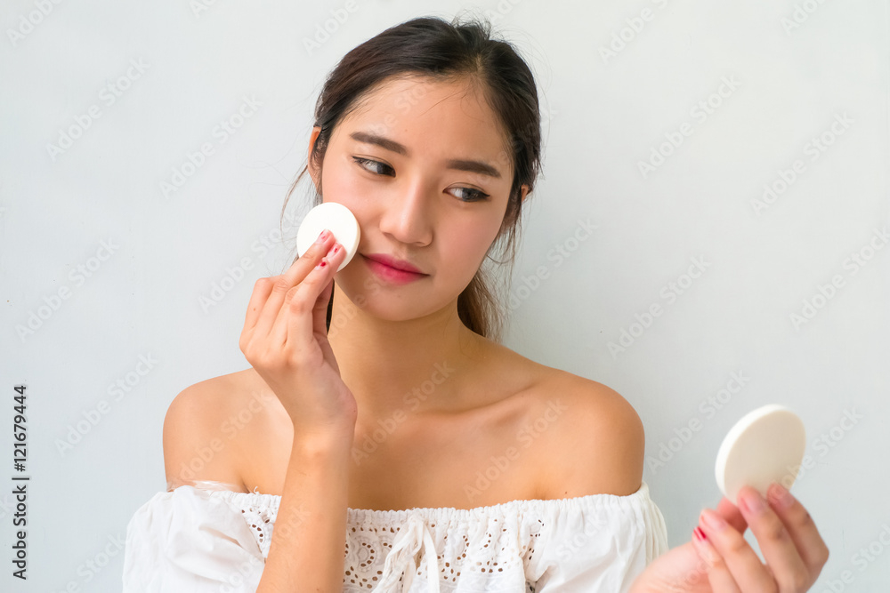 Young woman applying foundation on face with powder puff, Young woman applying foundation on face with powder puff,
