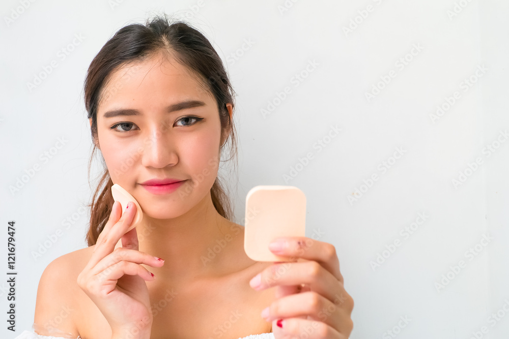 Young woman applying foundation on face with powder puff, Young woman applying foundation on face with powder puff,