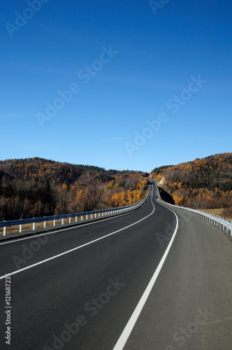 Highway in the Valley. Bright autumn landscape. The blue sky and mountains on the horizon. Used toning of the photo. © Евгений Кожевников