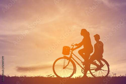 Silhouette women and boy with bicycle on sunset