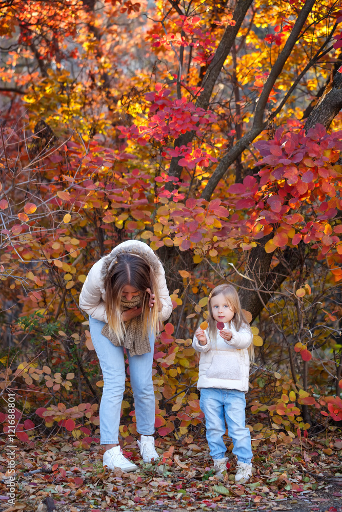 Mother and daughter collect autumn leaves. Mother and daughter collect autumn leaves.