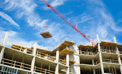 Concrete Highrise Construction site, with tower crane moving materials