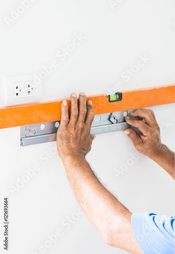 Asian Mans Hand Measuring A Wall With Spirit Level