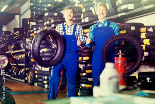 Two happy colleagues working with motorcycle tires