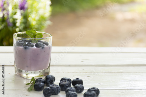 Yogurt Blue Berry and fresh berry on wooden white table on background outdoor view.Close up
