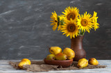 Still life: a set of pottery, a bouquet of sunflowers and pears on a wooden table. Natural light from the windows.