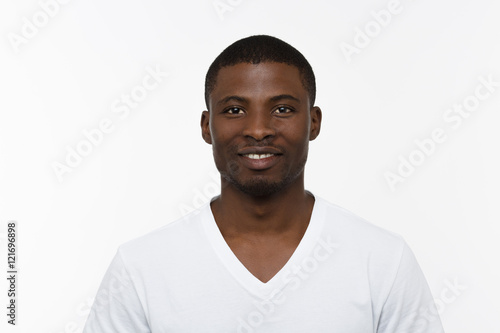 Portrait of African man smiling isolated on white background in studio. Handsome man in white T-shirt posing for photographer.