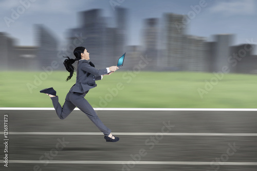 Young employee with laptop runs on track © Creativa Images