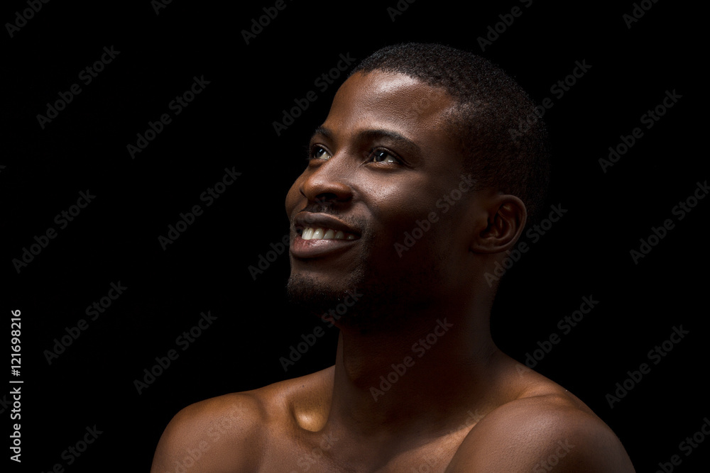 Portrait of happy naked black man smiling for camera while posing over black background in studio. Handsome man looking upwards. Portrait of happy naked black man smiling for camera while posing over black background in studio. Handsome man looking upwards.