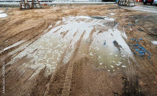 Puddle and mud with truck wheel track at construction site in rainy day photo