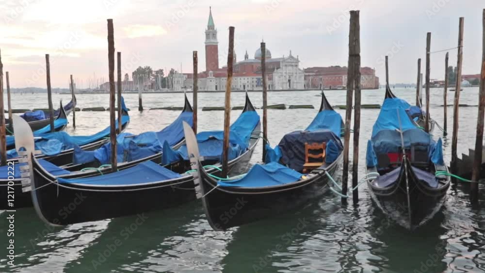 Gondolas moored by Saint Mark square in sunrise. San Giorgio di Maggiore church is in the background (Venice, Italy) Gondolas moored by Saint Mark square in sunrise. San Giorgio di Maggiore church is in the background (Venice, Italy)