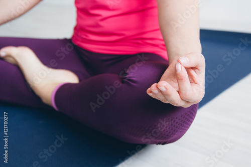 Young woman in a white room doing yoga exercises .