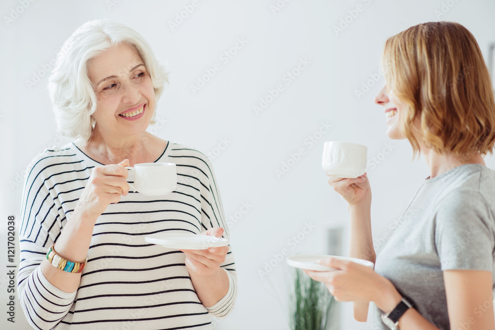 Cheerful senior woman and her adult daughter drinking coffee Cheerful senior woman and her adult daughter drinking coffee