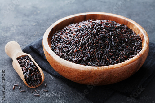 Black rice in wooden bowl on a dark table