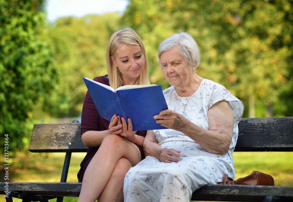 Young woman reading a book elderly woman in the park.