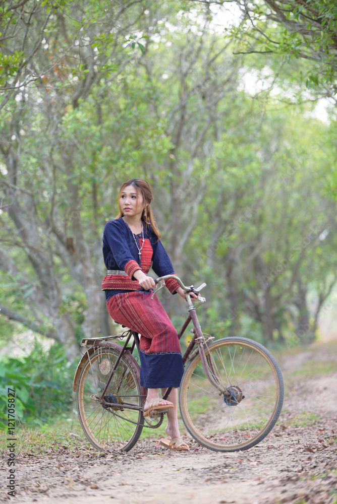 Young asian women sitting on an old bike in tribe dress in rice