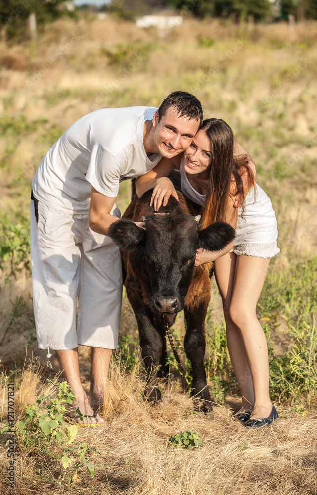young couple of farmers with a bull-calf young couple of farmers with a bull-calf