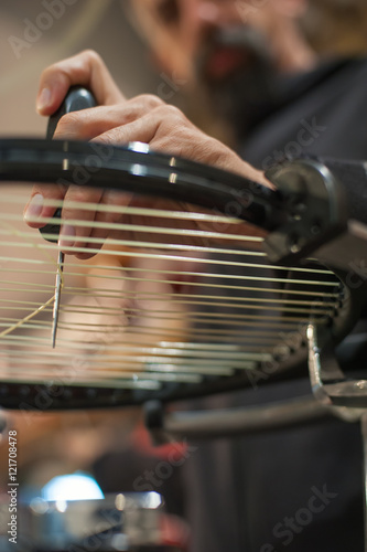 Stringing Machine. Detail of tennis stringer hands while holding awl and doing racket stringing