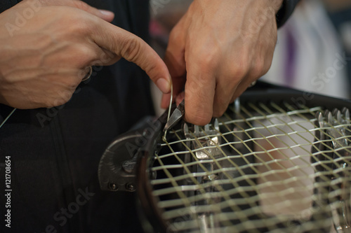 Stringing tennis racket. Tennis stringer tying knots and cutting string with pliers