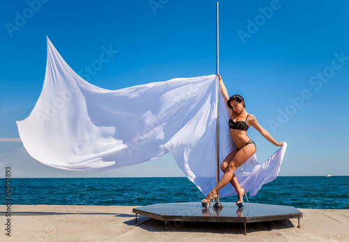 Female pole dancer against the sea and sky