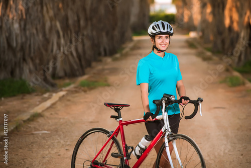 Portrait of young female cyclist standing with bike on palms off-road