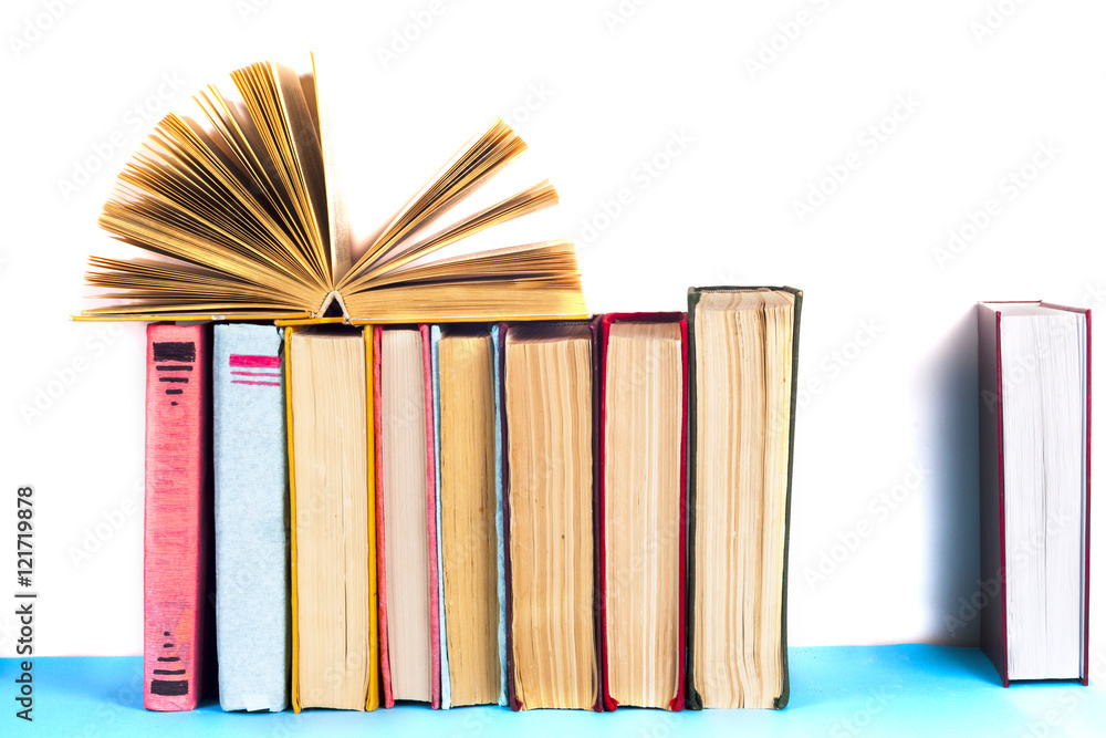 Obraz premium Open book, stack of colorful hardback books on light table. Back to school. Copy space for text