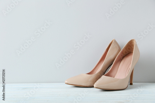 Pair of beige women's high-heeled shoes on wooden table