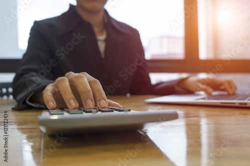 Businesswoman working on accounts using a calculator and laptop photo