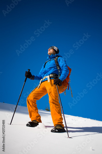 Mountain climber walks on a snowy slope.