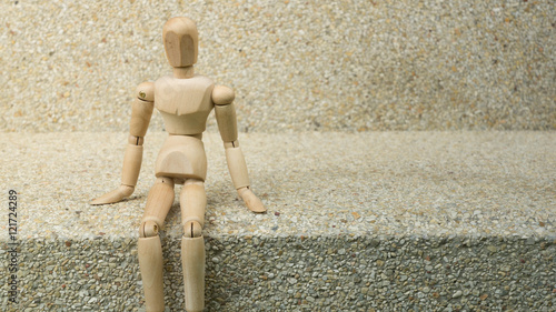 wooden human figure sit alone steps floor