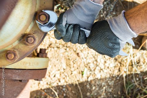 Hands with Work Gloves Holding a Wrench and Tighten very Rusty Bolts