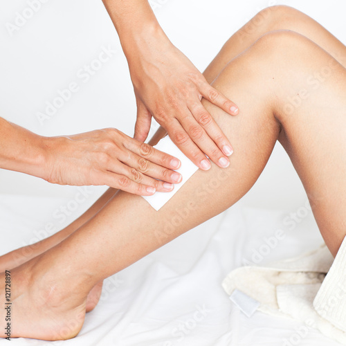 Removing hair from woman’s legs in a beauty spa during a beauty treatment