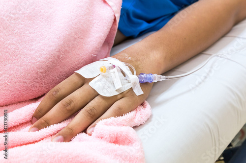 Patient hand in hospital with saline intravenous iv