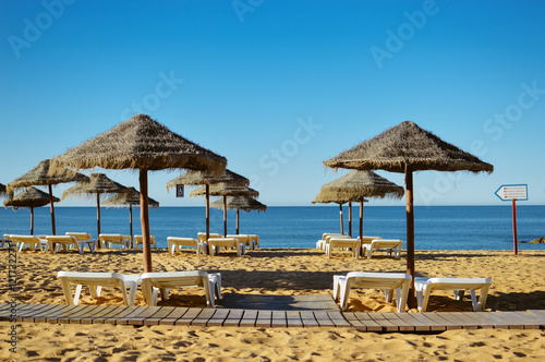 Blue sky and straw umbrella on a beautiful tropical beach background