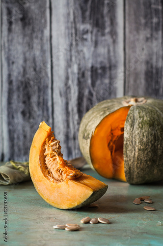 fetta di zucca in primo piano su base verde e zucca sfuocata sullo sfondo