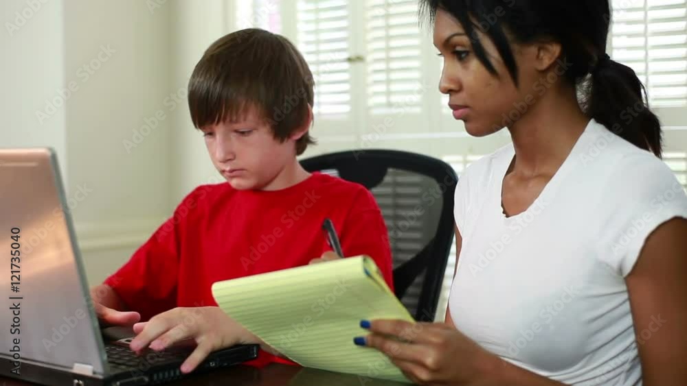Boy using laptop as his pretty African American tutor looks on. Focus starts on tutor then moves to student. Boy using laptop as his pretty African American tutor looks on. Focus starts on tutor then moves to student.